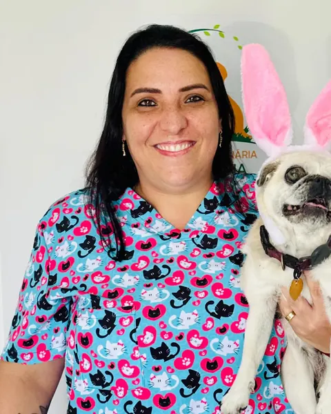 Dra. Camilla Gouveia sorrindo ao lado de um paciente canino.