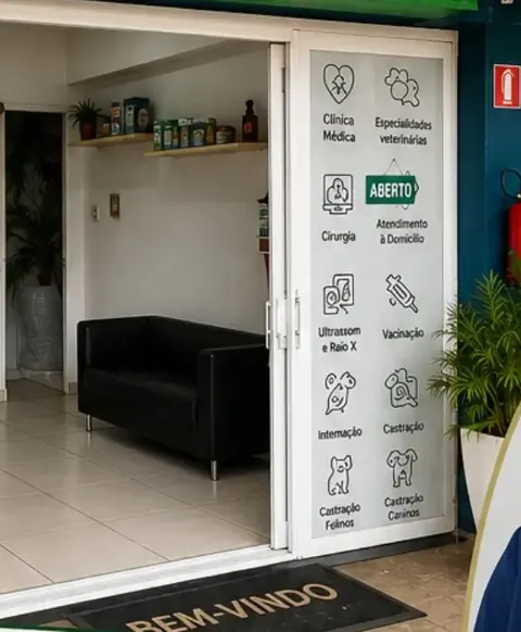 Recepção da Clínica Veterinária da Granja vista pela porta de vidro, com sofá preto e prateleira com produtos.